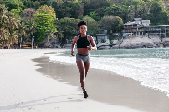 Black sportswoman running near sea