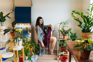 Barefoot female sitting near plants in studio