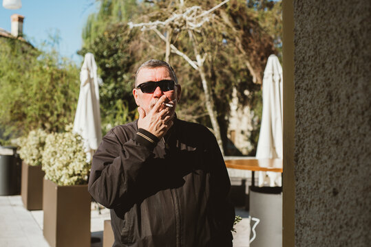 A middle-aged man smoking cigarette on a street 