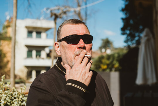 A middle-aged man smoking cigarette on a street 