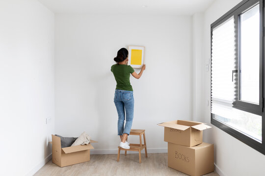 woman hanging a picture at new home