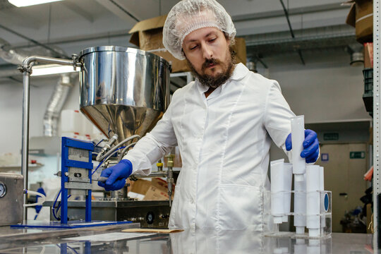 Male worker sealing tubes on manual machine