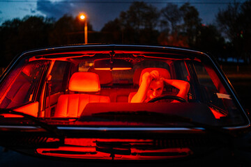 Woman in black car with red neon light