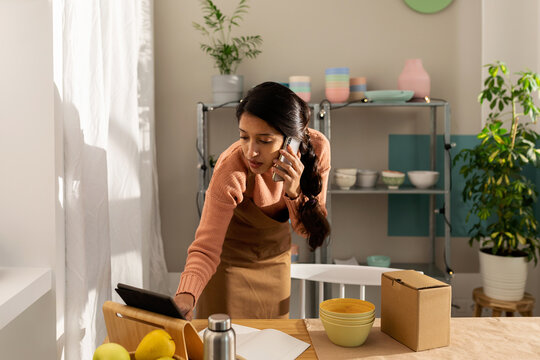 Woman calling by phone and using her tablet at workplace