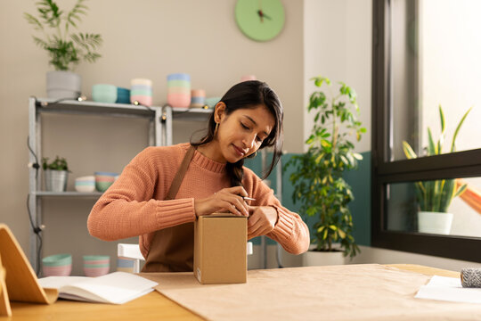 Young woman packing an ecological bowl at online store