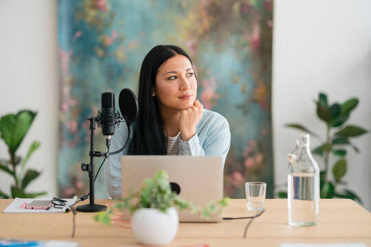 Pensive woman preparing for recording podcast and looking away