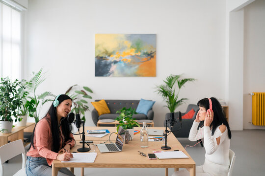 Asian women in headphones recoding podcast together in studio