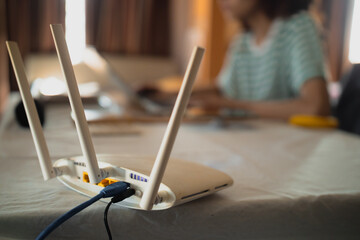 A woman is working at home using a modem router, connecting the Internet to her laptop.