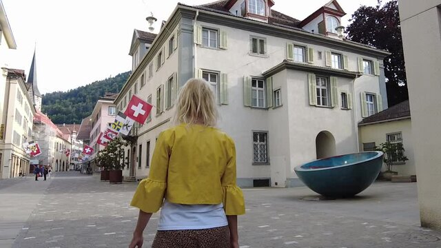 Girl tourist walking at sunset in the downtown roads of Chur city. Coira Swiss town in Grisons canton. Coira capital town of the Grisons Swiss canton of Switzerland. SLOW MOTION