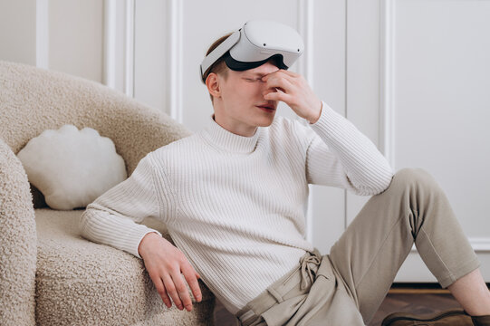 Tired man with VR headset rubbing eyes
