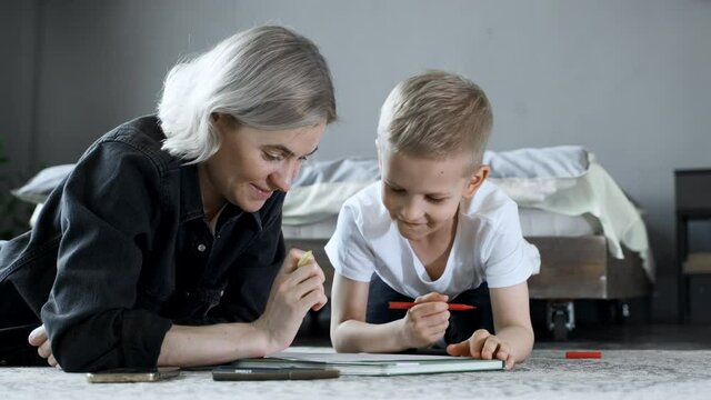 A Young Mother and a Boy Child Are lying on the Floor, Drawing with Felt-Tip Pens on Paper, Studying, Talking and Having Fun