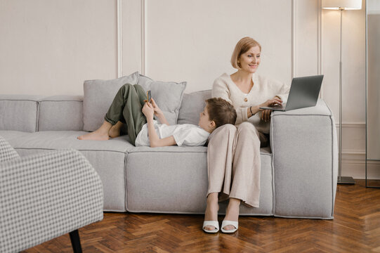 Mother and son using gadgets in living room at home