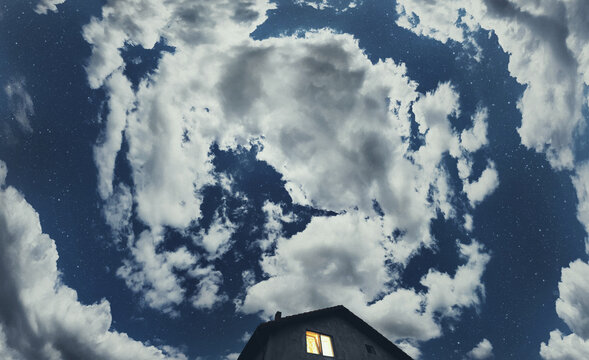Sky with clouds and stars over house at night
