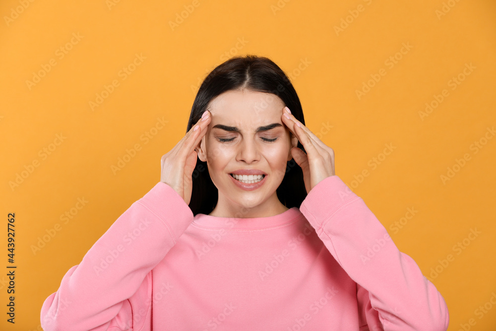 Wall mural Woman suffering from migraine on yellow background