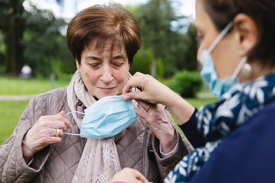 Elderly lady putting a mask on her face outdoors