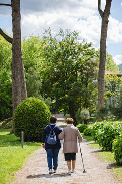 Elderly lady accompanied by her caregiver for a walk in the park