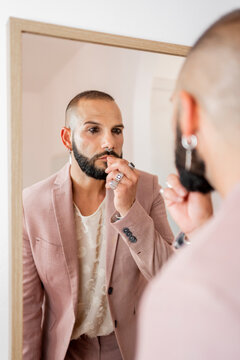 Modern man with makeup looking at mirror