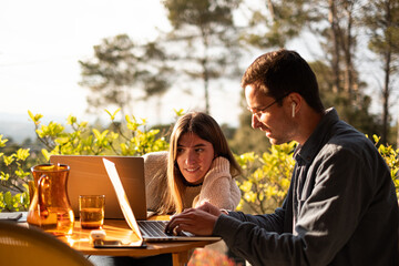 Couple remote working together with laptop on terrace 
