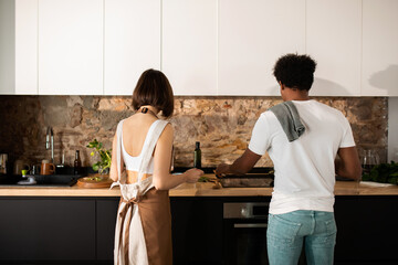 Young couple from back cooking at modern kitchen