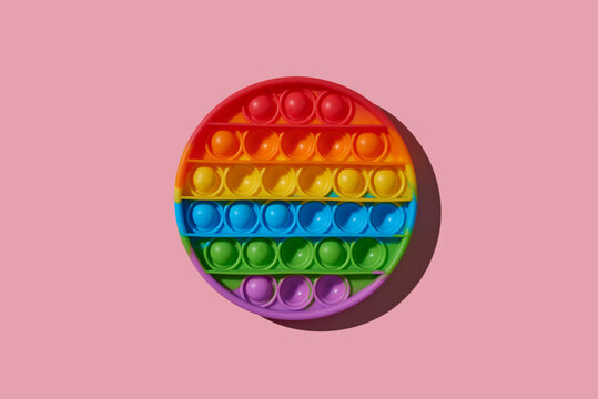 rainbow destressing toy on a pink background