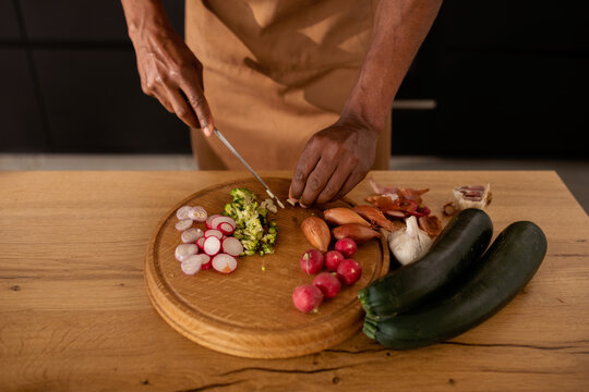 Top view of male arms cutting fresh vegetables on the table