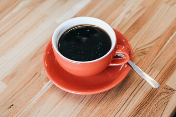 Hand holding hot cup of coffee on wood table. Morning cup of coffee. Hipster tone. Selective focus, blur background.