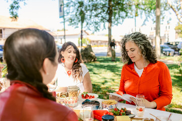 Woman reading book during picnic with friends