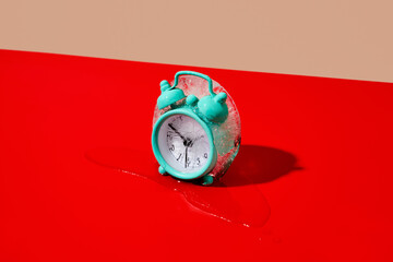 frozen alarm clock melting on a red surface