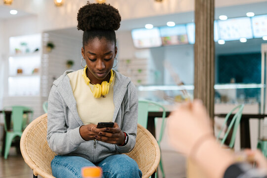 Afro woman in a restaurant using her smart phone