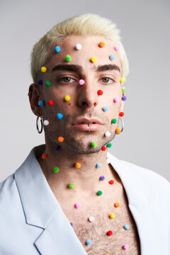 Stylish male model with colorful pellets on skin
