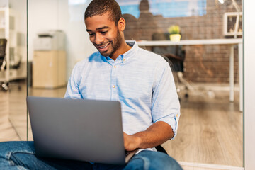 Pensive black creative man working on laptop  in empty office