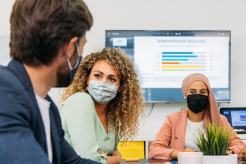 Crop multiethnic coworkers in cloth face masks speaking in office