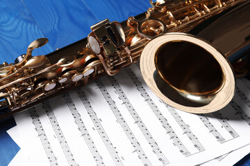 Obraz premium Beautiful saxophone and note sheets on blue wooden background, closeup
