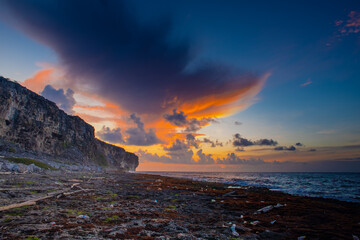 The sun rises on the bluff in Cayman Brac but sadly it brings to light the amount of trash that has washed up on the coastline - obrazy, fototapety, plakaty