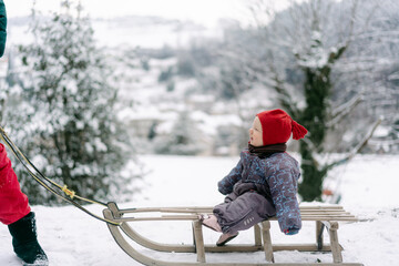 baby girl sitting  on a sled in the snow