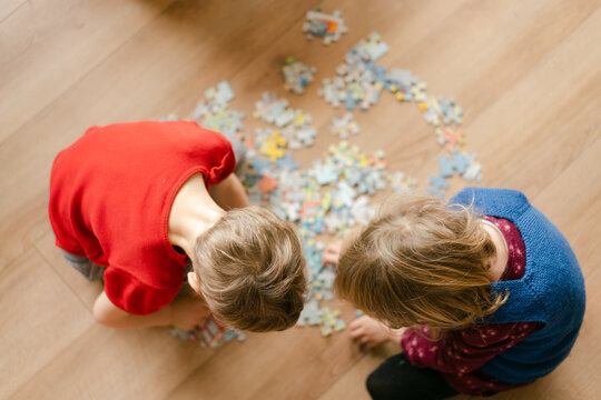 from above view of siblings solving a jigsaw puzzle 