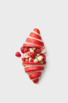 Croissant with raspberries and roses buds on white background
