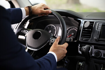 Naklejka premium Man driving his car, closeup view of hands on steering wheel