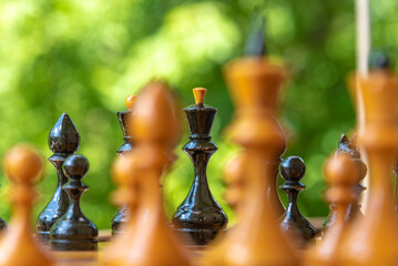 Chess pieces of shabby old chess pieces on a chessboard close up - black king in selective focus