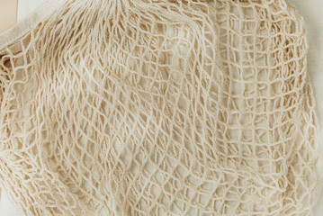 Beige reusable cotton mesh bags on beige background.  Eco-friendly shopping bag. Close up.  Zero waste grocery concept. Sustainable lifestyle with no plastic
