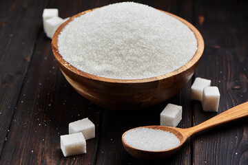 Bowl and scoop with white sand and thick sugar on wooden background