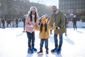 Happy family spending time together at outdoor ice skating rink