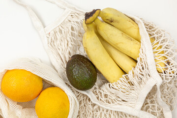 Fresh fruits, vegetables in eco cotton bags on beige table. Carrots, oranges, bananas, avocado from market. Zero waste shopping concept. Sustainable lifestyle with no plastic
