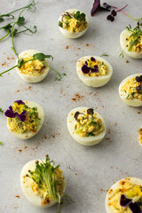 Eggs stuffed with sauce and fried onions with various microgreens, top view, delicious healthy protein snack