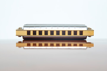The harmonica lies on a mirrored surface. Classical musical wind instrument.