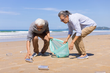 Senior couple collecting rubbish at the beach. environmental protection concept and Good role model.