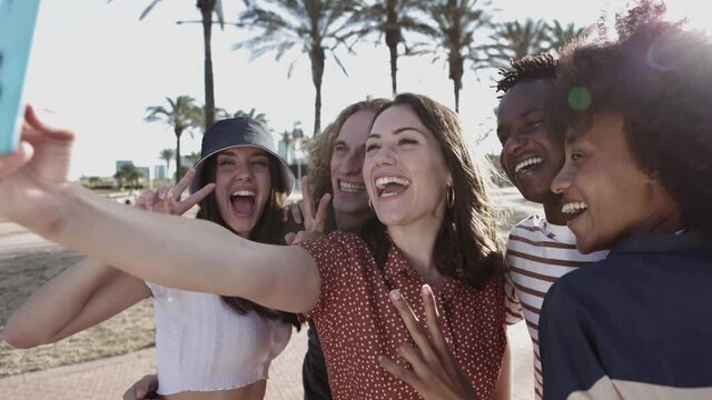 Happy multiracial people taking a selfie with mobile phone outdoors - Multiethnic friends in summer clothes having fun on holidays in the beach