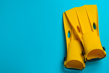 Pair of yellow flippers on light blue background, flat lay. Space for text © New Africa