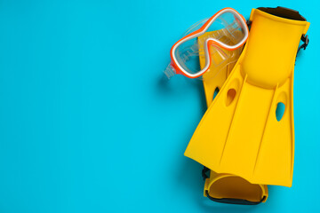 Pair of yellow flippers and mask on light blue background, flat lay. Space for text © New Africa