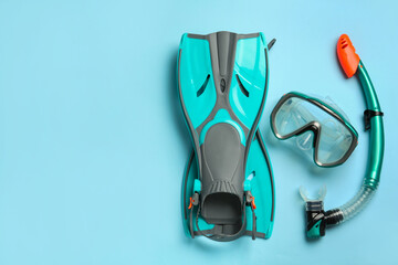 Pair of turquoise flippers and mask on light blue background, flat lay. Space for text © New Africa